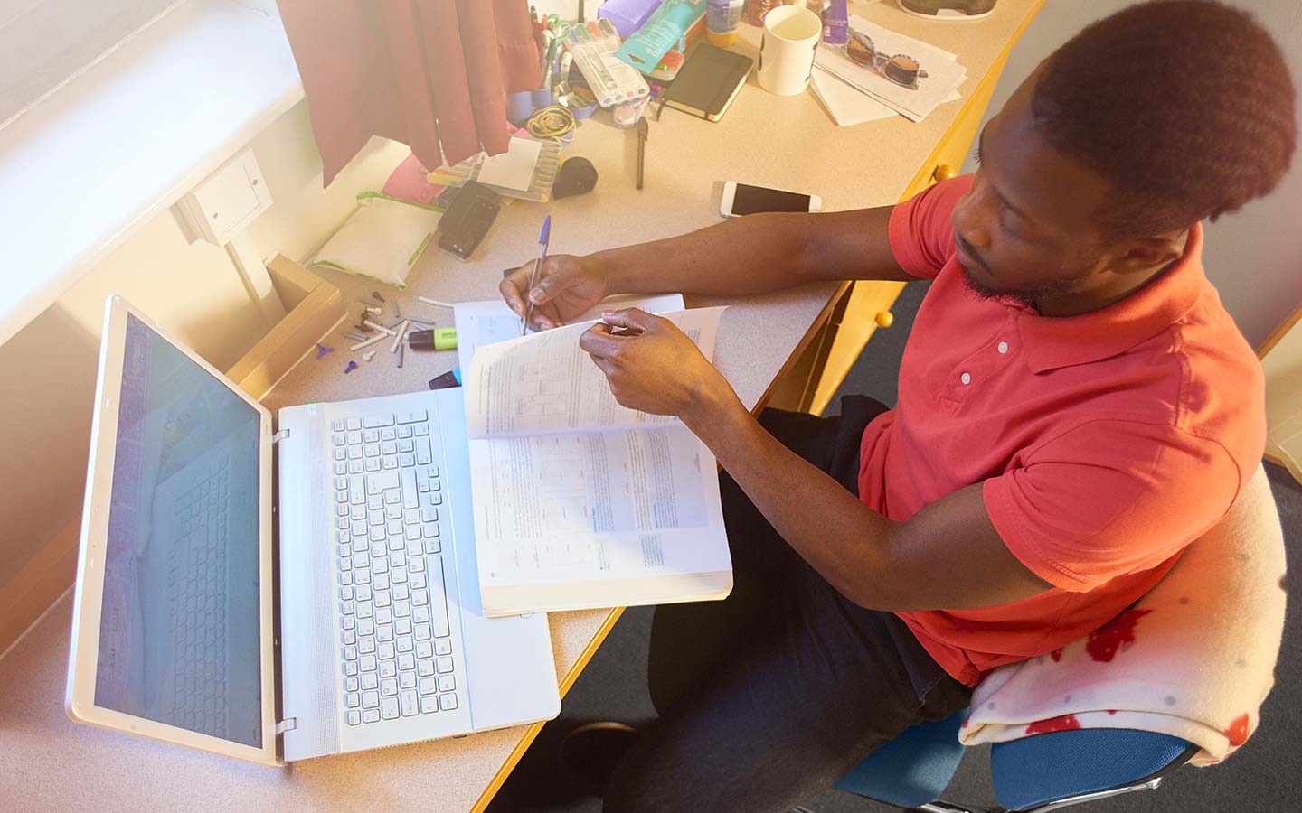 A student at a desk with laptop and notebook