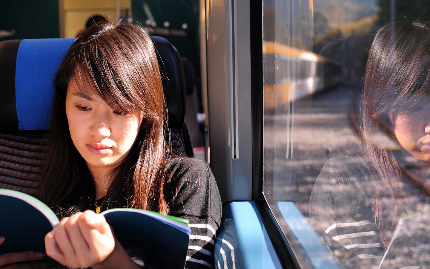A student reading a book on a train