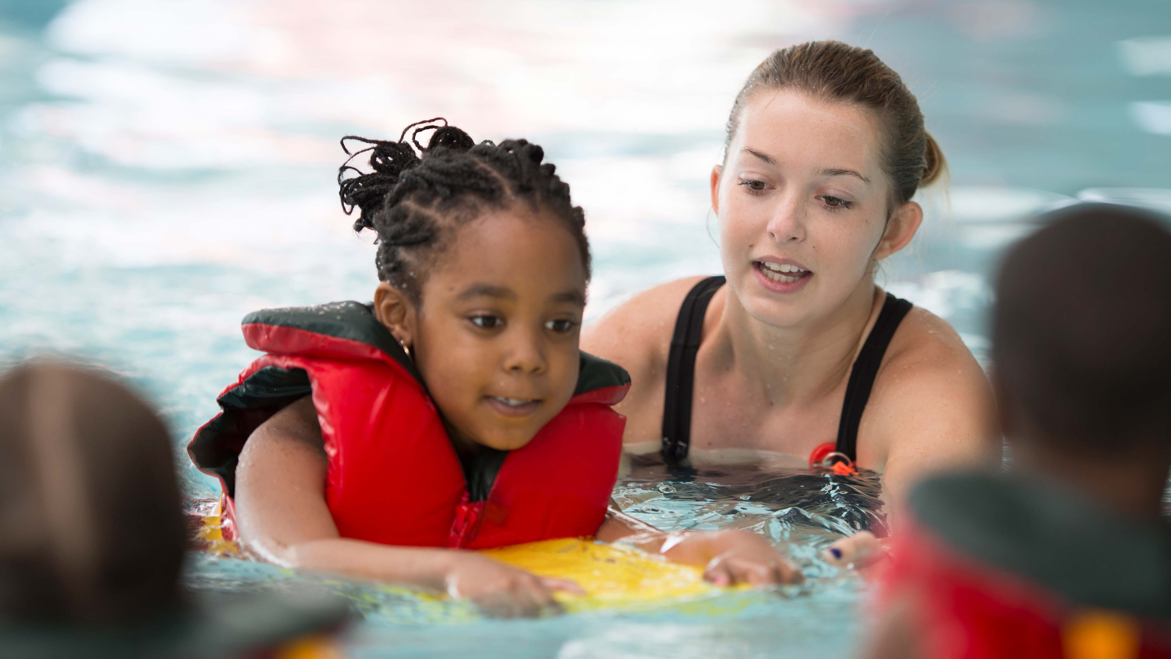 A woman giving a swimming lesson to children