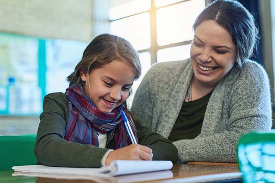 An educator is giving one-to-one support as a child writes