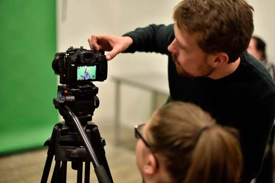Lecturer teaches a student about camera settings in the studio