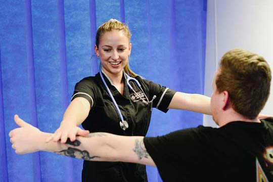 An Osteopath checks her patient's range of arm movements