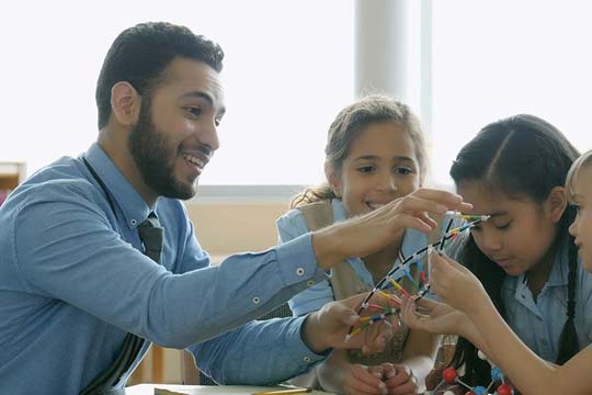 A biology teacher and his pupils pass round a model of DNA