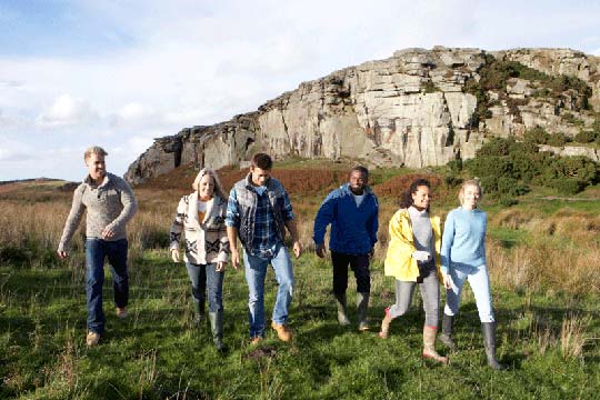 A group of trainee geography teachers walking on Dartmoor with a tor behind them