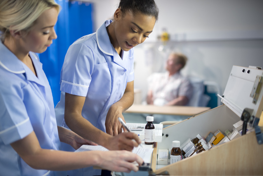 Two nurses talking at a nursing station in a hospital ward