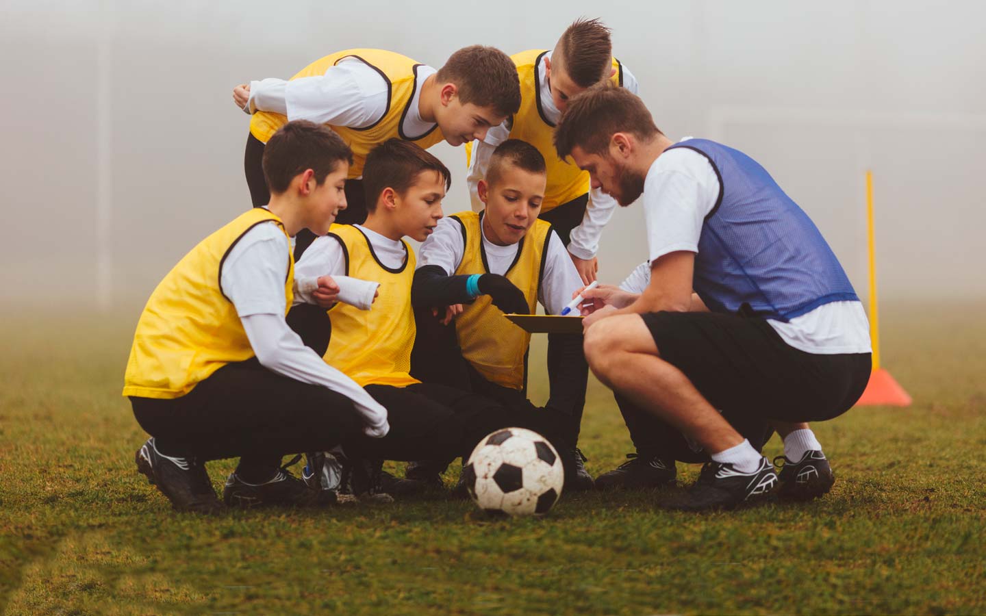 Young footballers huddle around their coach